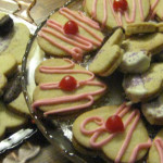 Photo of heart shaped cookies decorated with pink and purple icing and red cherries
