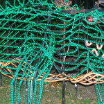 Wire framed gator outlined in green twinkle lights.